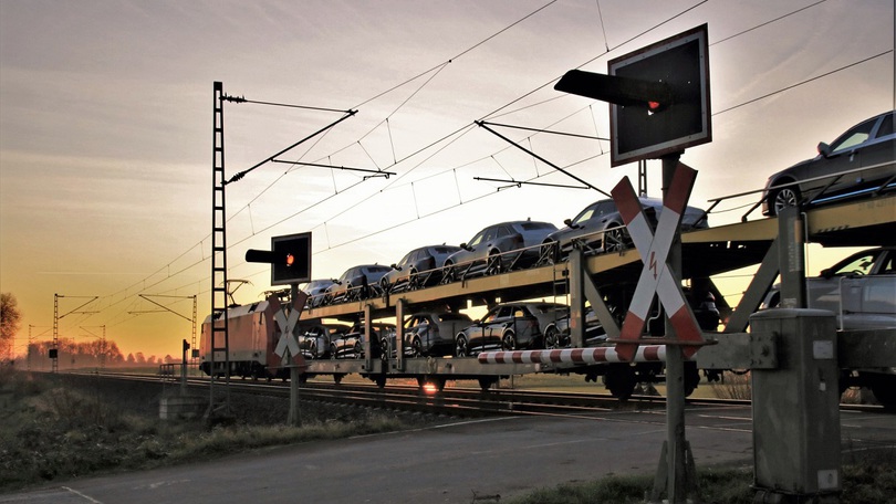 Ein Autotransport-Zug überquert einen Bahnübergang