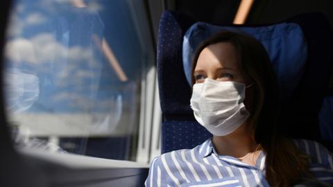 Eine Frau mit Mund-Nasen-Bedeckung unterwegs im ICE des DB Fernverkehr
