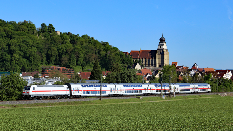 Eine Bahn fährt an einer Ortschaft vorbei.