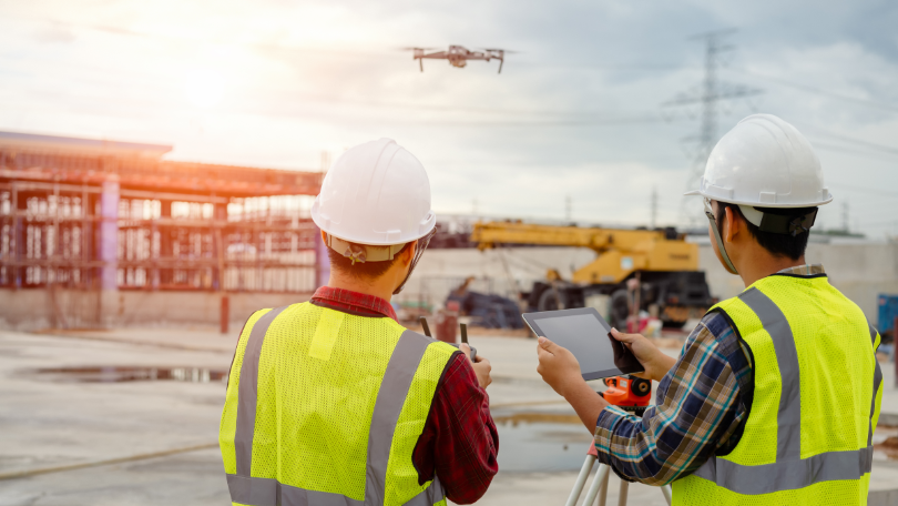 Bauarbeiter steuern eine Drohne über einer Baustelle